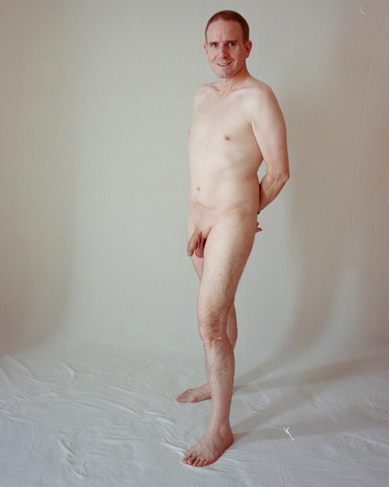 SJ Nude standing fully nude with hands behind his back, white backdrop, Kodak Portra 400