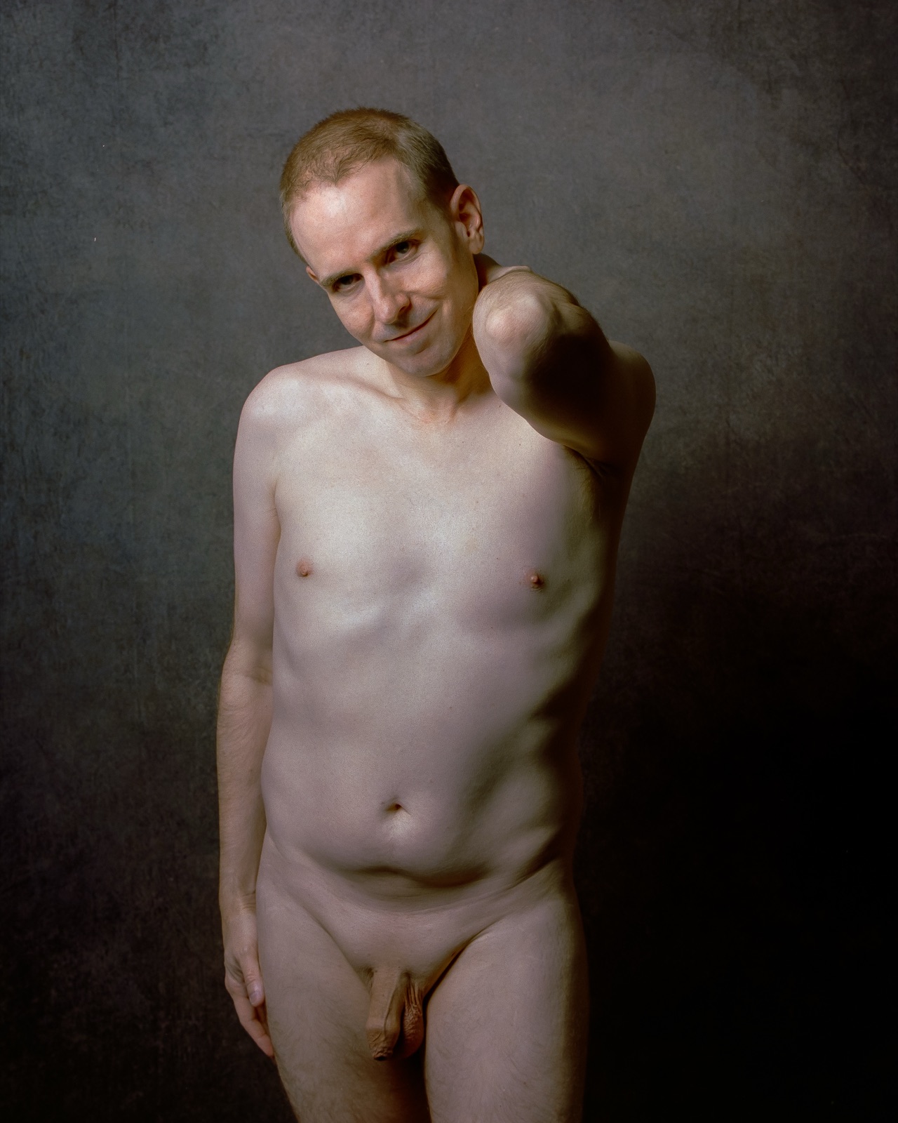 SJ Nude standing fully nude with a hand on his shoulder, gray backdrop, Portra 400, San Jose