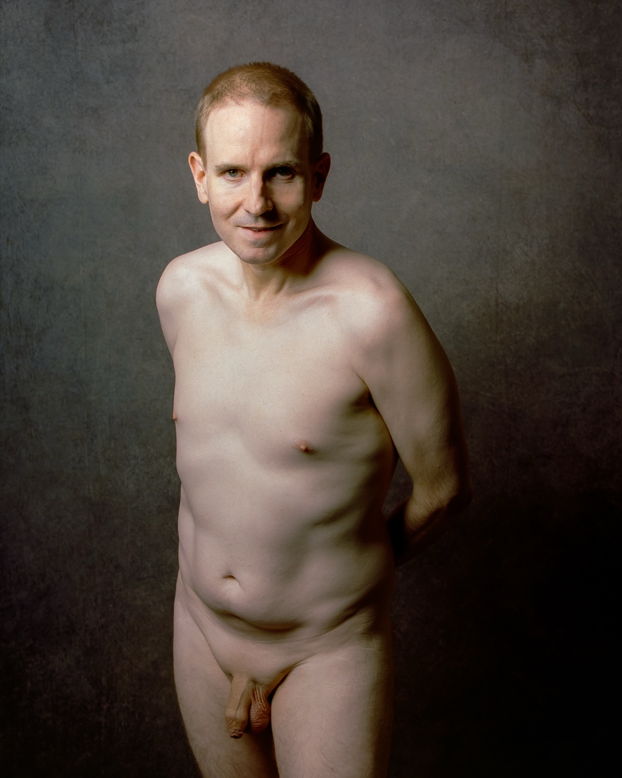 SJ Nude standing fully nude with a hand behind his back, gray backdrop, Portra 400, San Jose