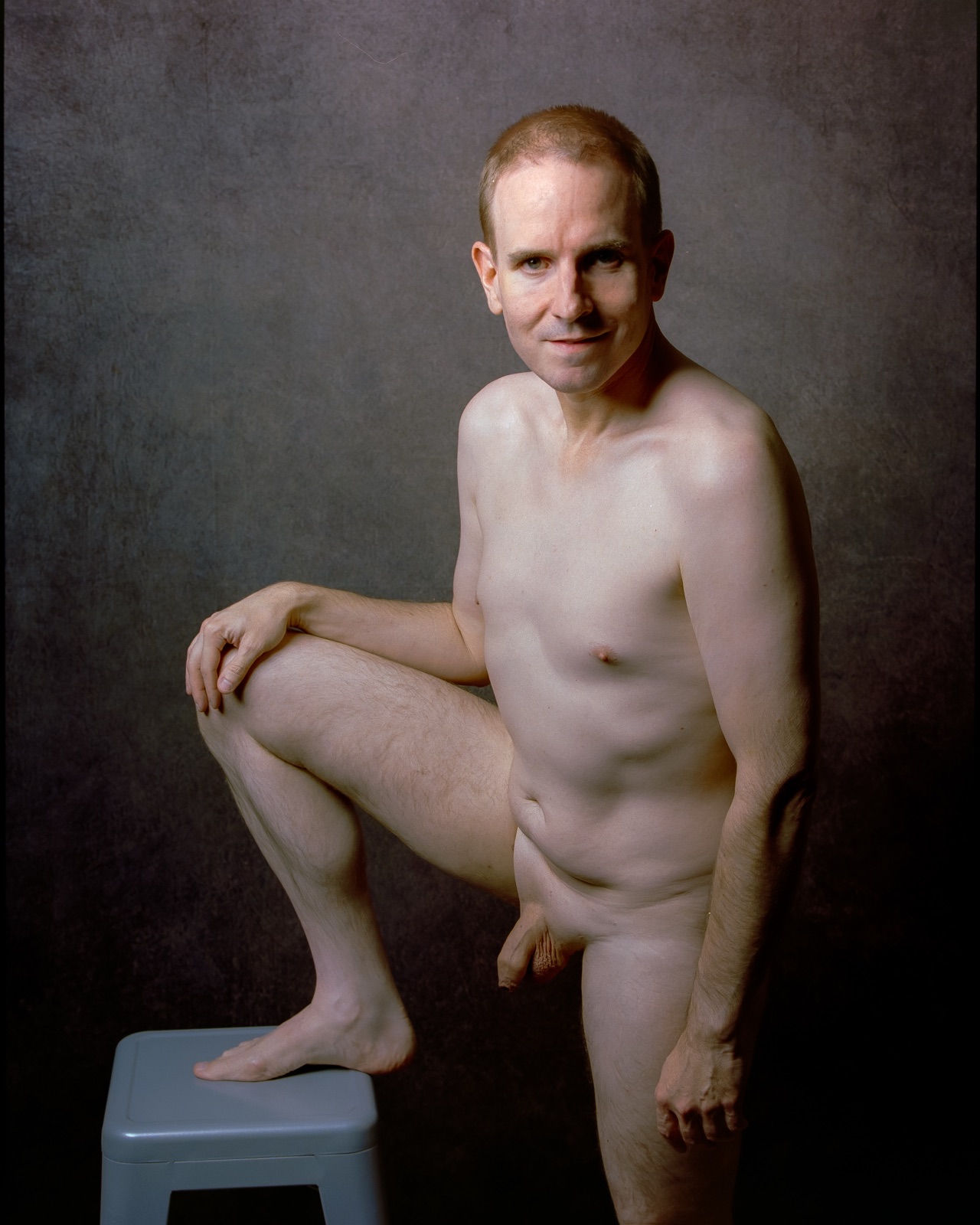 SJ Nude standing fully nude with one foot on a stool, gray backdrop, medium format Kodak Portra 400, San Jose