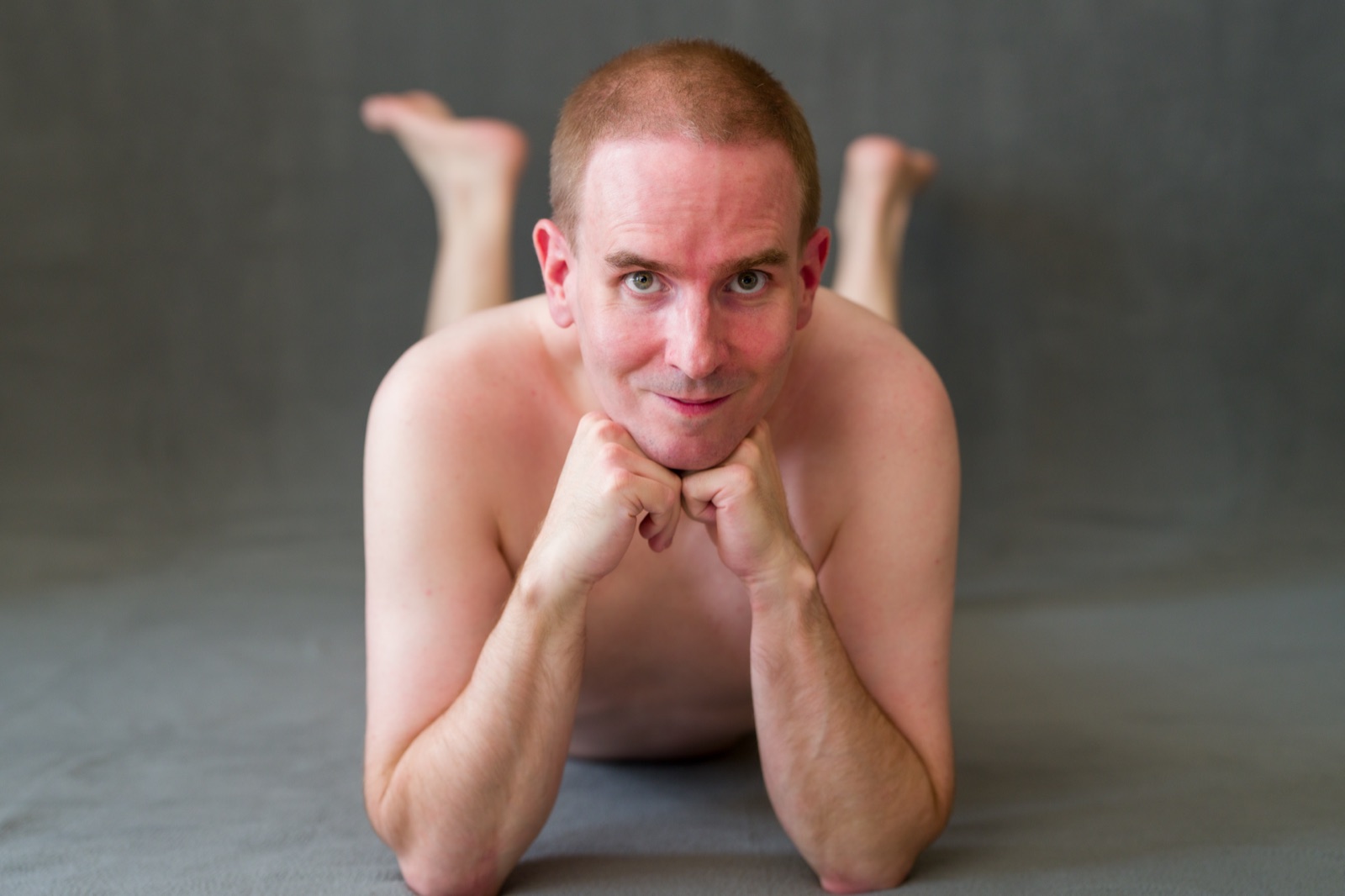 SJ Nude lying on his stomach with fists under his chin, San Jose studio portrait